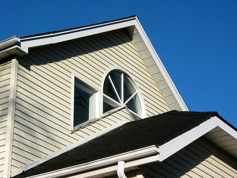 Close up of the side of a home with beige vinyl siding